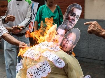 Un grupo de personas quema un muñeco con la foto de la cara de Nicolás Maduro