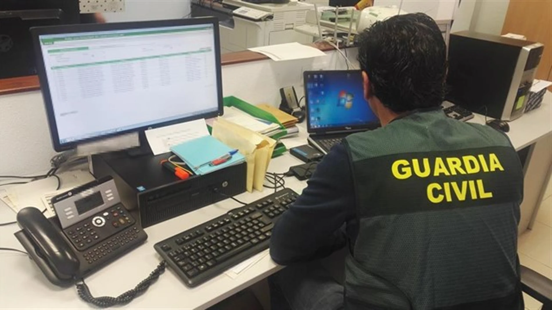 Imagen de archivo de un guardia civil consultando dos ordenadores Imagen de archivo de un guardia civil consultando dos ordenadores