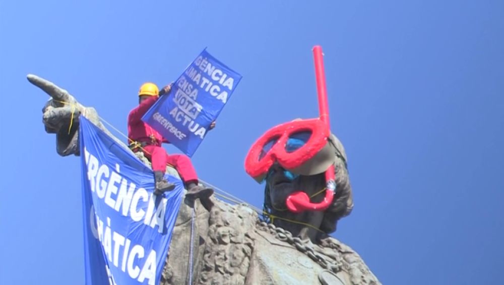 Dos activistas de Greenpeace colocan unas gafas de buzo a la estatua de Colón en Barcelona