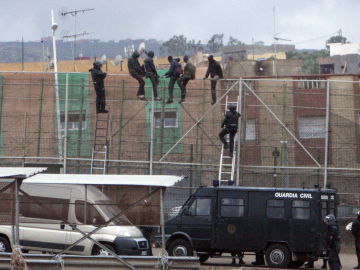 Imagen de archivo de migrantes subidos a la valla de Melilla