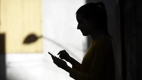 Imagen de archivo de una joven mirando su móvil. Imagen de archivo de una joven mirando su móvil.