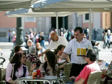 Un camarero sirve bebidas en una terraza en la plaza de la Virgen de Valencia Un camarero sirve bebidas en una terraza en la plaza de la Virgen de Valencia