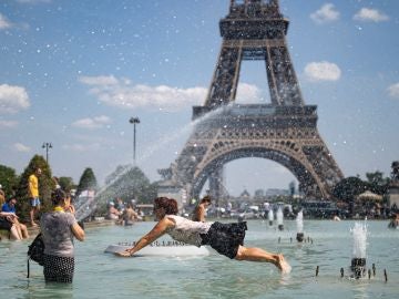 Personas refrescándose en la fuente de la Plaza del Trocadero, frente a la Torre Eiffel en París