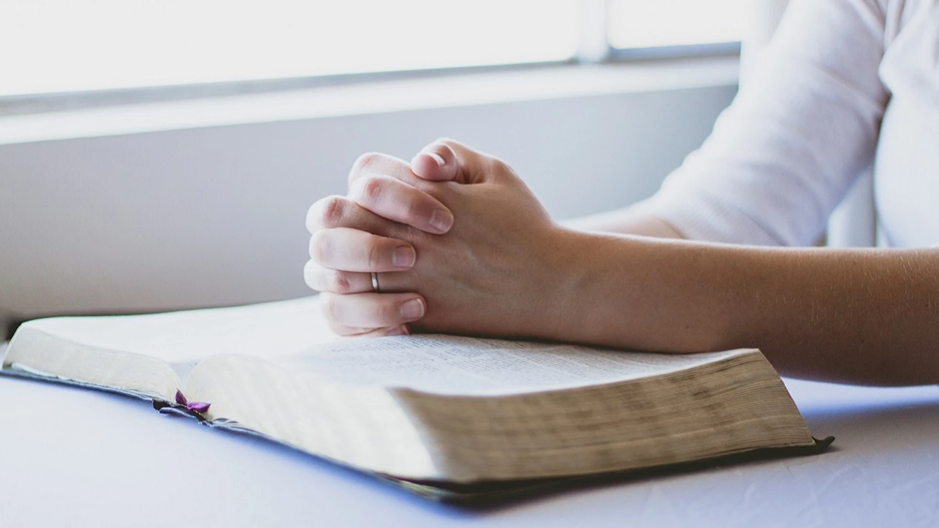 Una persona rezando sobre una Biblia Una persona rezando sobre una Biblia