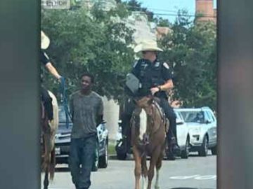 Dos policías llevan maniatado a un hombre negro detenido