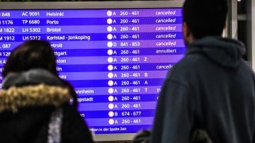 Unos pasajeros mirando los vuelos cancelados en la pantalla informativa