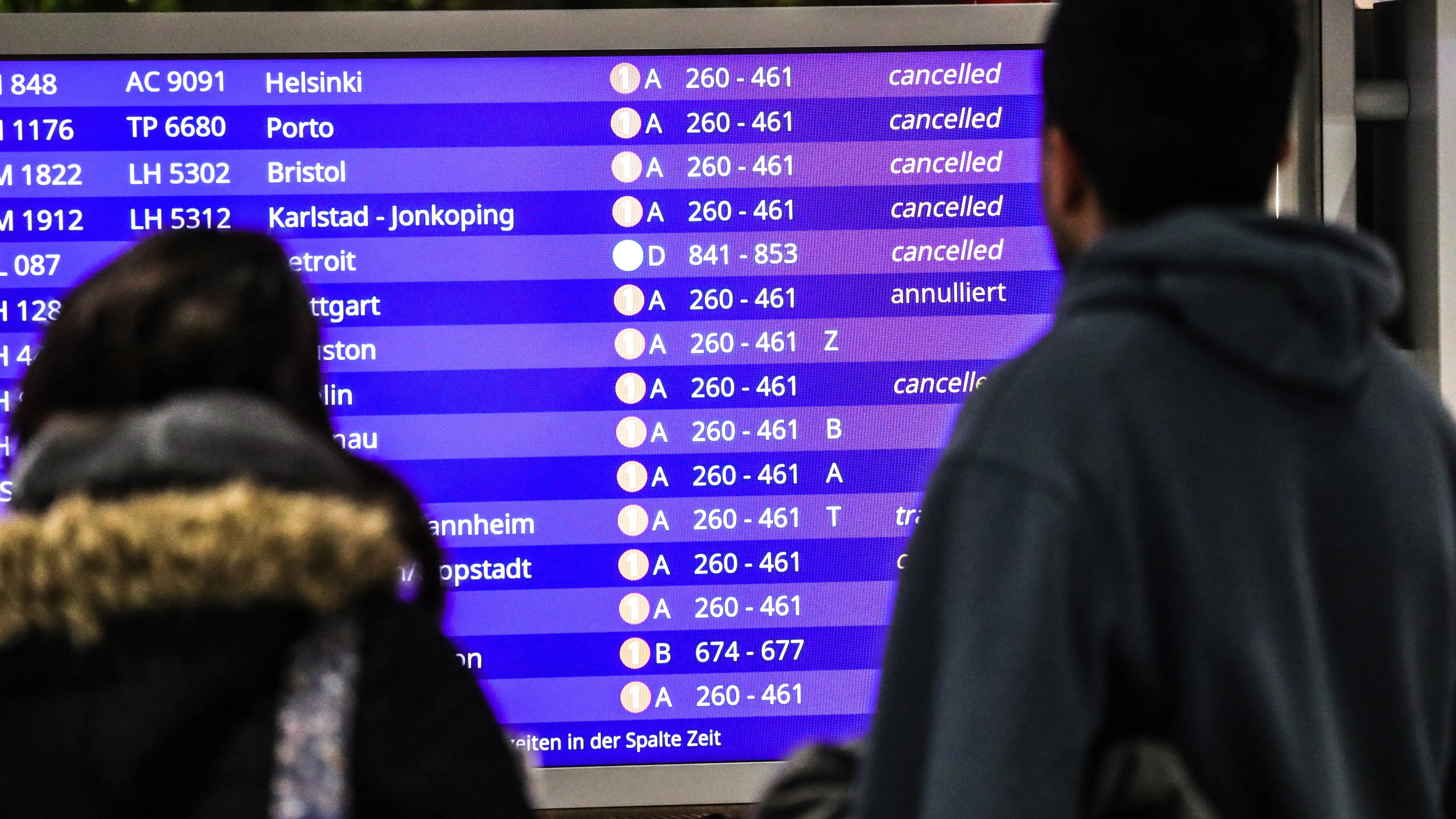 Unos pasajeros mirando los vuelos cancelados en la pantalla informativa