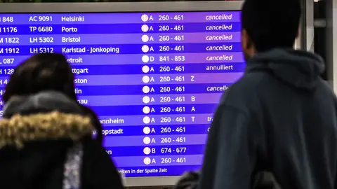Pasajeros miran los vuelos cancelados en una pantalla informativa Pasajeros miran los vuelos cancelados en una pantalla informativa