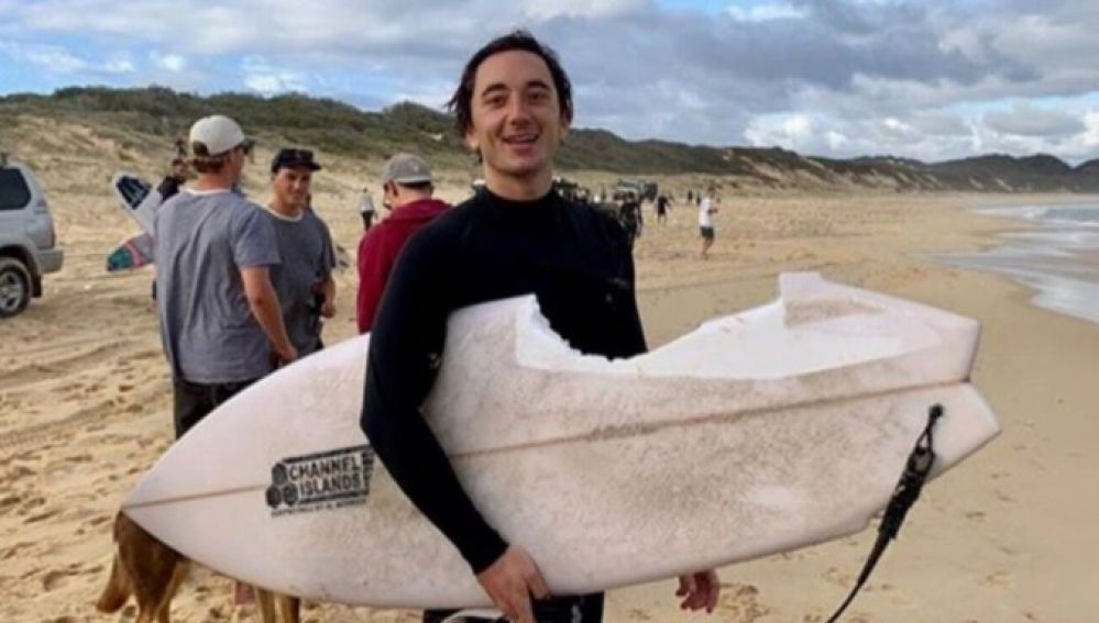 Mike Bruton posa con su tabla de surf tras el ataque del tiburón