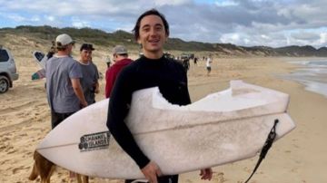 Mike Bruton posa con su tabla de surf tras el ataque del tiburón