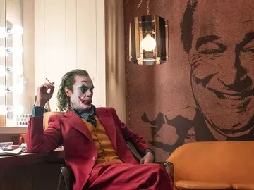 Joker (Joaquin Phoenix) con una imagen al fondo de Murray Franklin (Robert De Niro) Joker (Joaquin Phoenix) con una imagen al fondo de Murray Franklin (Robert De Niro)