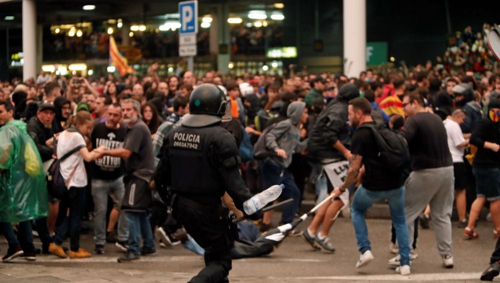 Un mosso d'esquadra durante una de las cargas contra las miles de personas se agolpan ante el Aeropuerto del Prat después de que la plataforma Tsunami Democràtic haya llamado a paralizar la actividad del aeropuerto, en protesta por la condena a los líderes del 'procés'.