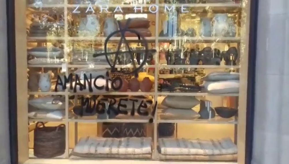 Un grupo de manifestantes escribe "Amancio muérete" en una tienda de Zara de Girona