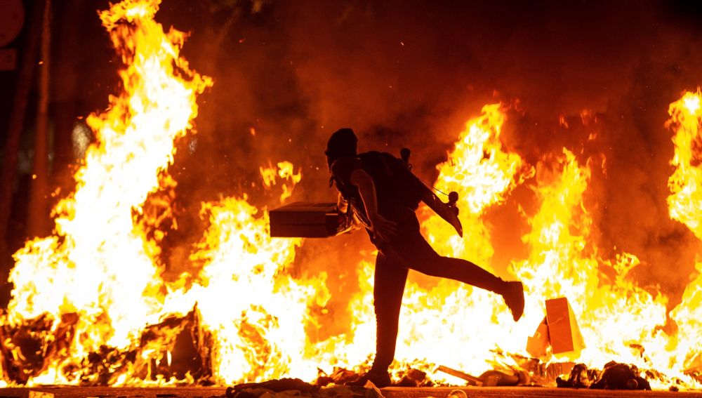 Un manifestante echa al fuego un cartón junto a la Delegación del Gobierno en Barcelona