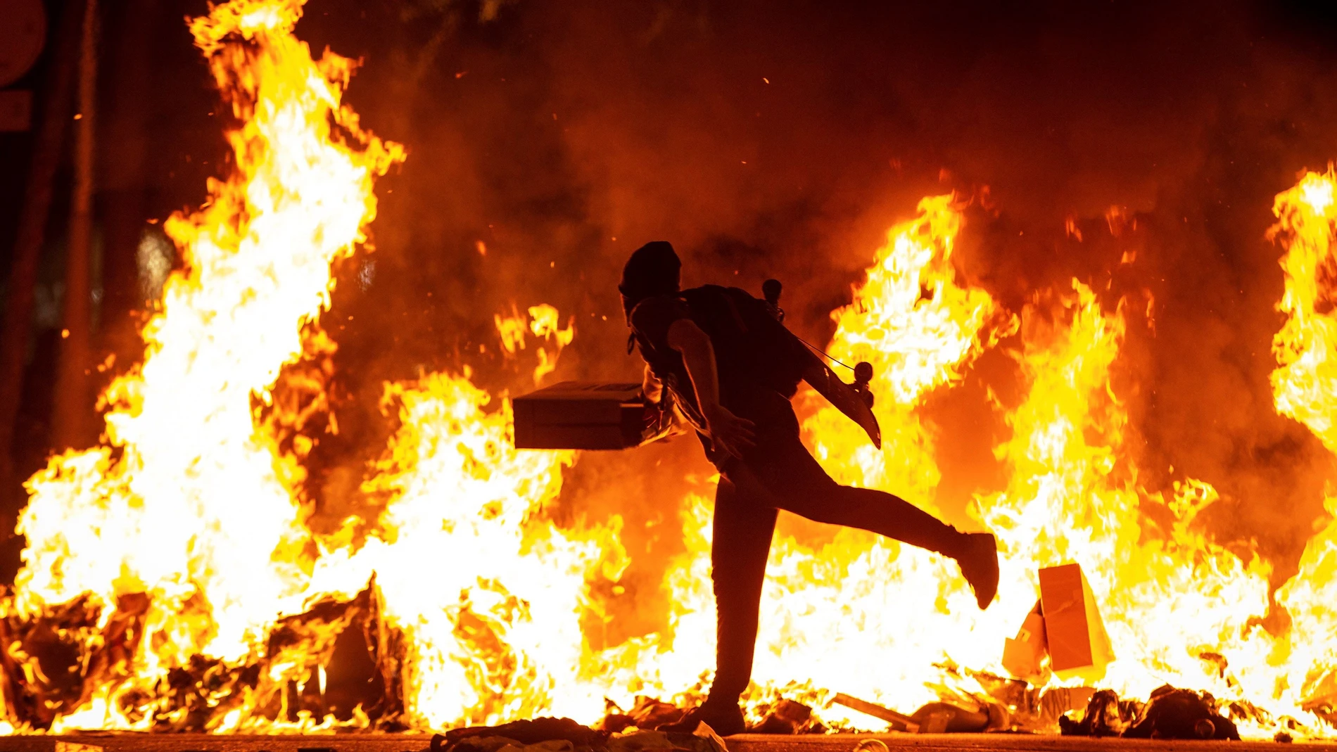 Un manifestante echa al fuego un cartón junto a la Delegación del Gobierno en Barcelona Un manifestante echa al fuego un cartón junto a la Delegación del Gobierno en Barcelona