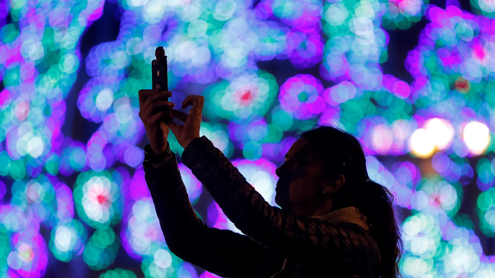Una joven fotografía el árbol de Navidad de la Puerta del Sol. Una joven fotografía el árbol de Navidad de la Puerta del Sol.