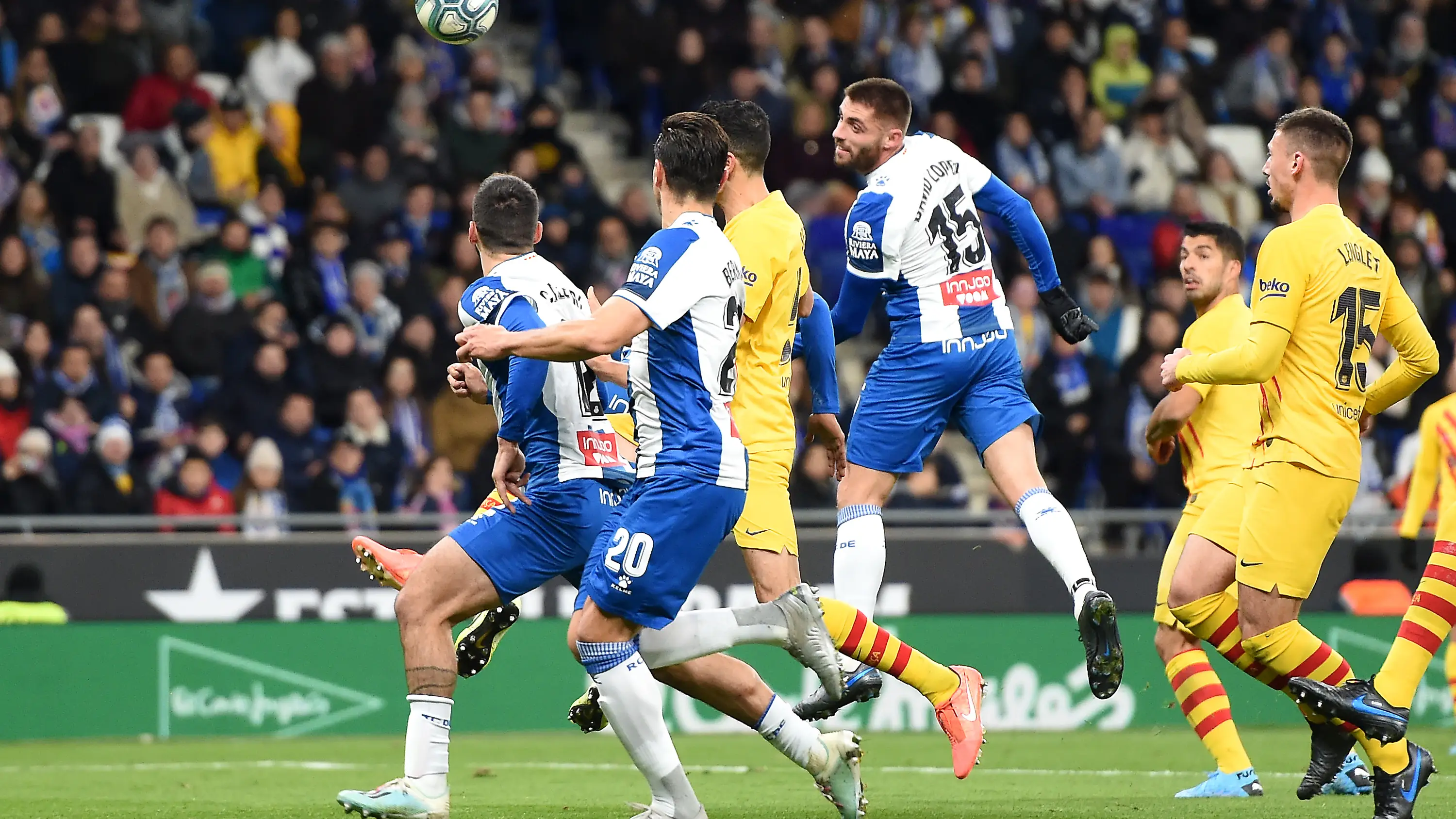 Los jugadores de Espanyol y Bar&ccedil;a disputan un bal&oacute;n a&eacute;reo