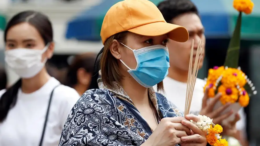 Una mujer se protege con una mascarilla Una mujer se protege con una mascarilla