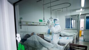 Un sanitario atendiendo a un paciente en un hospital de Wuhan, China