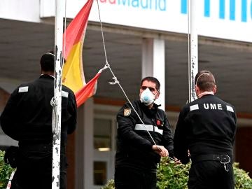 Miembros de Unidad Militar de Emergencias recogen la bandera de España en los exteriores del hospital Príncipe de Asturias de Madrid
