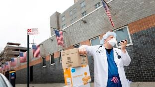 Un sanitario habla por tel&eacute;fono en Nueva York con la mascarilla puesta