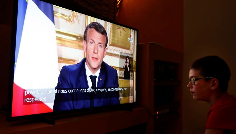 Un joven ve la comparecencia de Emmanuel Macron por televisión