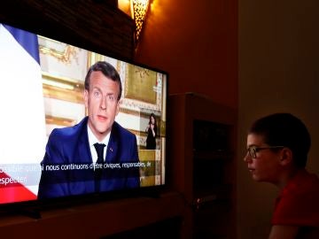 Un joven ve la comparecencia de Emmanuel Macron por televisión