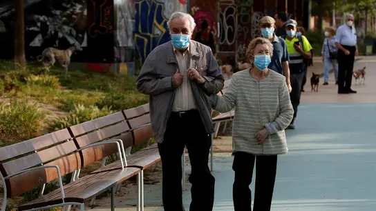 Una pareja protegida con mascarillas pasea por la Rambla Nova de Sants Una pareja protegida con mascarillas pasea por la Rambla Nova de Sants