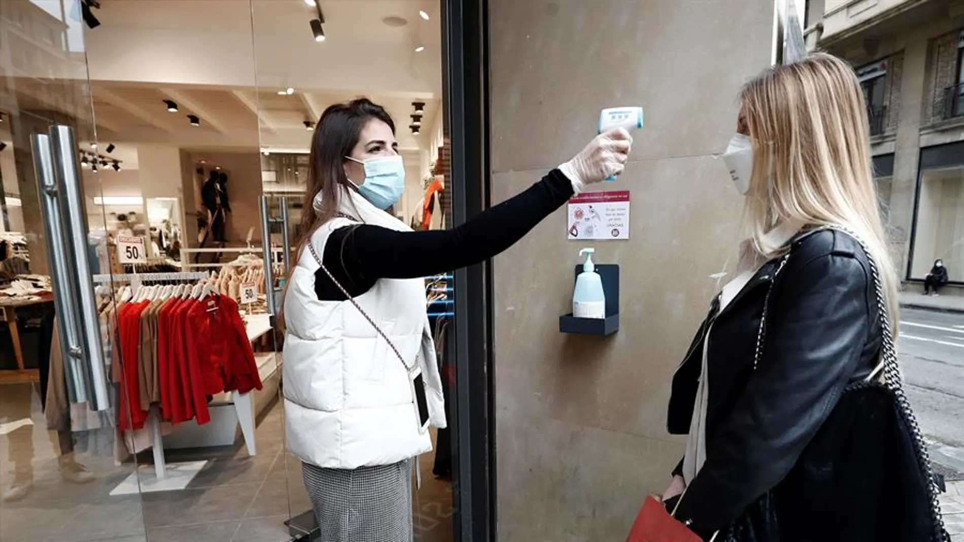 La encargada de una tienda de ropa toma la temperatura a una trabajadora La encargada de una tienda de ropa toma la temperatura a una trabajadora