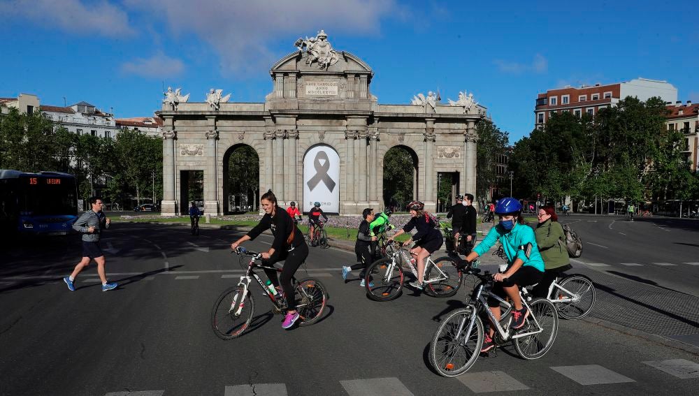 Vista de la Puerta de Alcalá con un crespón negro junto a la gente haciendo deporte en Madrid
