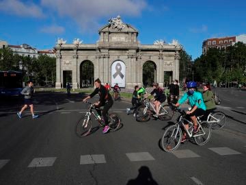 Vista de la Puerta de Alcalá con un crespón negro junto a la gente haciendo deporte en Madrid