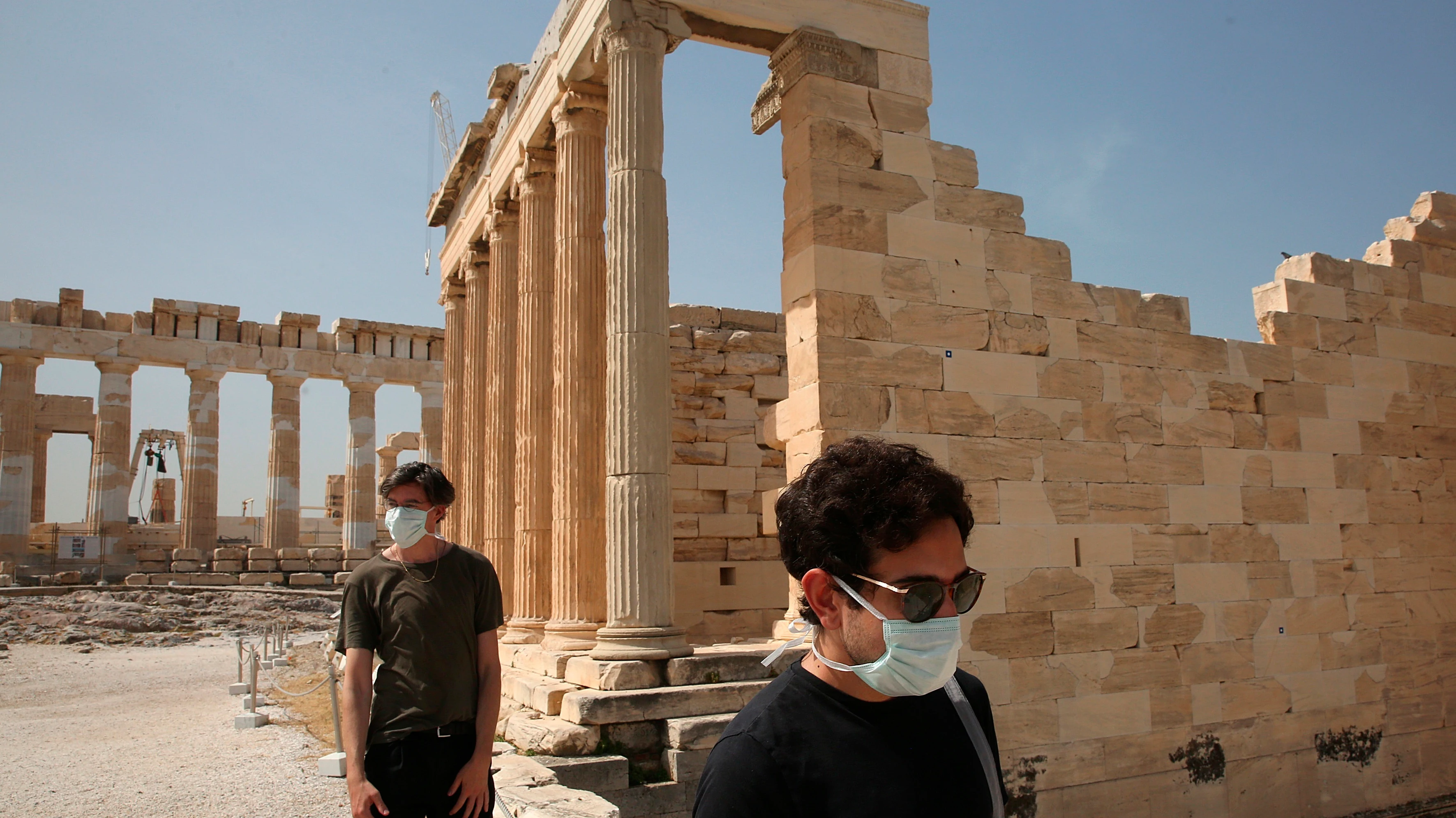 Dos turistas con mascarilla en la Acrópolis de Atenas Dos turistas con mascarilla en la Acrópolis de Atenas