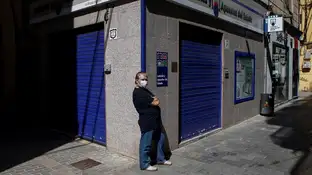Un ciudadano con mascarilla frente a una administración de lotería en Barcelona Un ciudadano con mascarilla frente a una administración de lotería en Barcelona