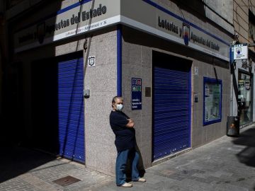 Un ciudadano con mascarilla frente a una administración de lotería en Barcelona