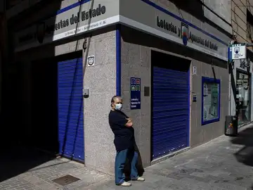 Un ciudadano con mascarilla frente a una administración de lotería en Barcelona Un ciudadano con mascarilla frente a una administración de lotería en Barcelona
