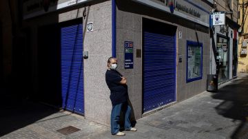 Un ciudadano con mascarilla frente a una administración de lotería en Barcelona