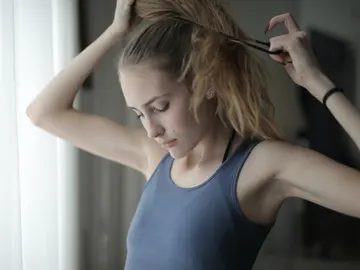 Chica haciéndose una coleta Chica haciéndose una coleta