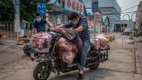 Un hombre con mascarilla montado en su moto en Pekín, China Un hombre con mascarilla montado en su moto en Pekín, China
