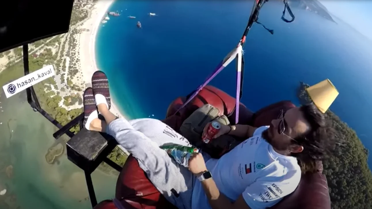 Un hombre vuela en parapente sentado tranquilamente en un sof&aacute; mientra se toma un aperitivo
