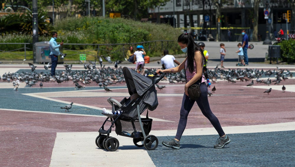 Una mujer con mascarilla empujando un carrito de bebé en Barcelona