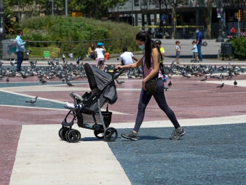 Una mujer con mascarilla empujando un carrito de bebé en Barcelona