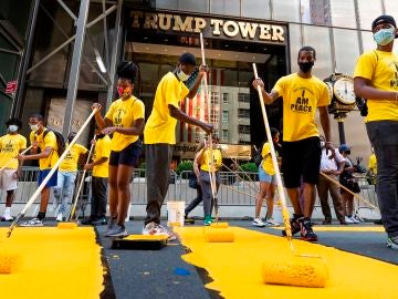 Voluntarios ponen los toques finales al enorme eslogan amarillo de "Black Lives Matter" en la calzada frente a la Torre Trump de Nueva York