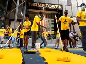 Voluntarios ponen los toques finales al enorme eslogan amarillo de "Black Lives Matter" en la calzada frente a la Torre Trump de Nueva York Voluntarios ponen los toques finales al enorme eslogan amarillo de "Black Lives Matter" en la calzada frente a la Torre Trump de Nueva York
