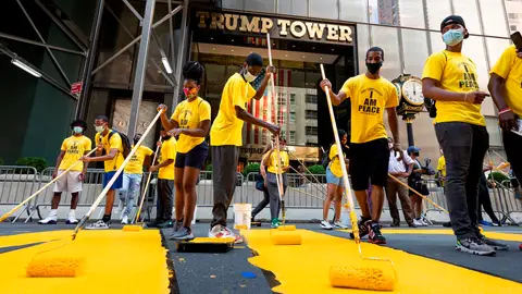 Voluntarios ponen los toques finales al enorme eslogan amarillo de "Black Lives Matter" en la calzada frente a la Torre Trump de Nueva York Voluntarios ponen los toques finales al enorme eslogan amarillo de "Black Lives Matter" en la calzada frente a la Torre Trump de Nueva York