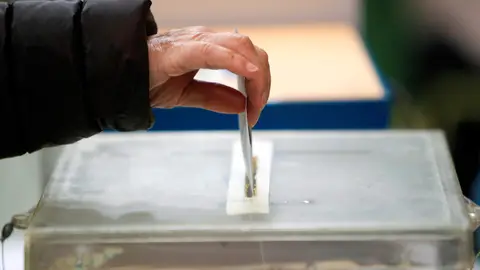 Una persona deposita su papeleta en una urna. Elecciones gallegas 12-J