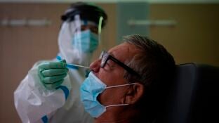 Una profesional sanitaria realiza una prueba PCR a un paciente en el CAP Raval Nord de Barcelona