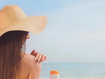 Mujer echándose crema solar en la playa Mujer echándose crema solar en la playa
