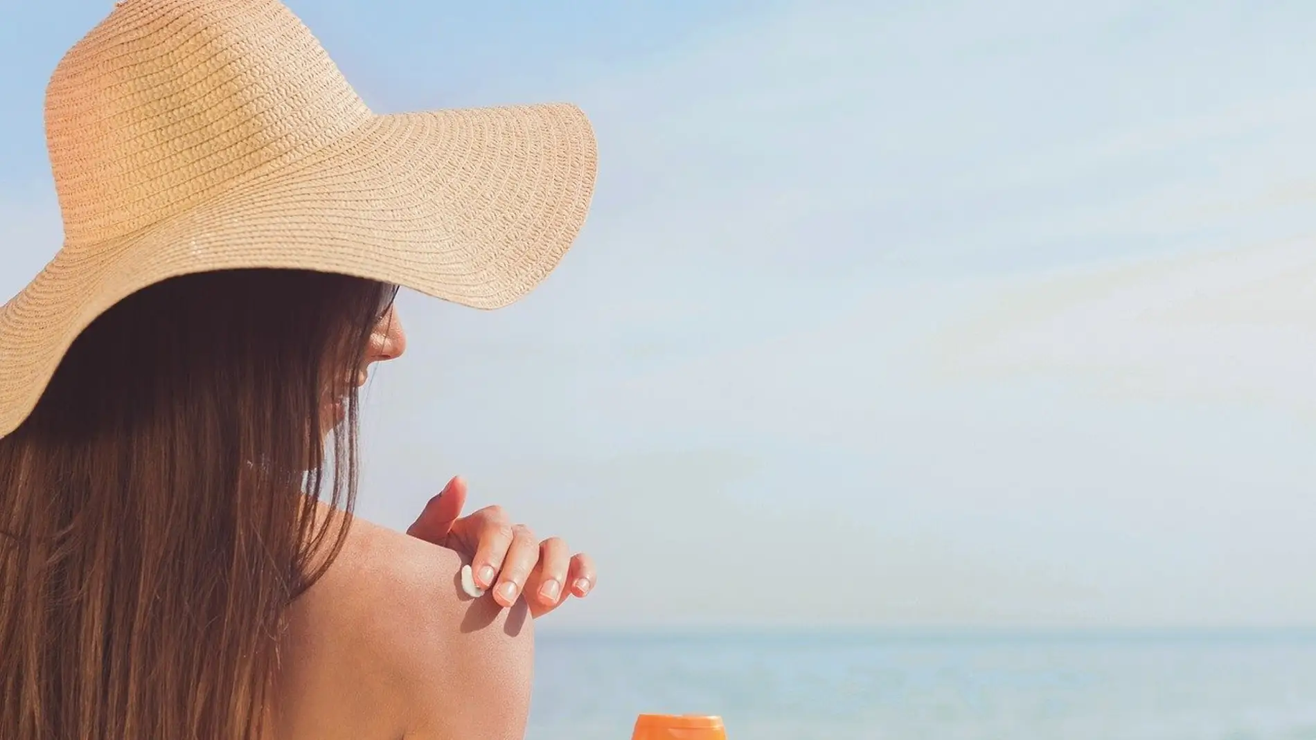 Mujer echándose crema solar en la playa