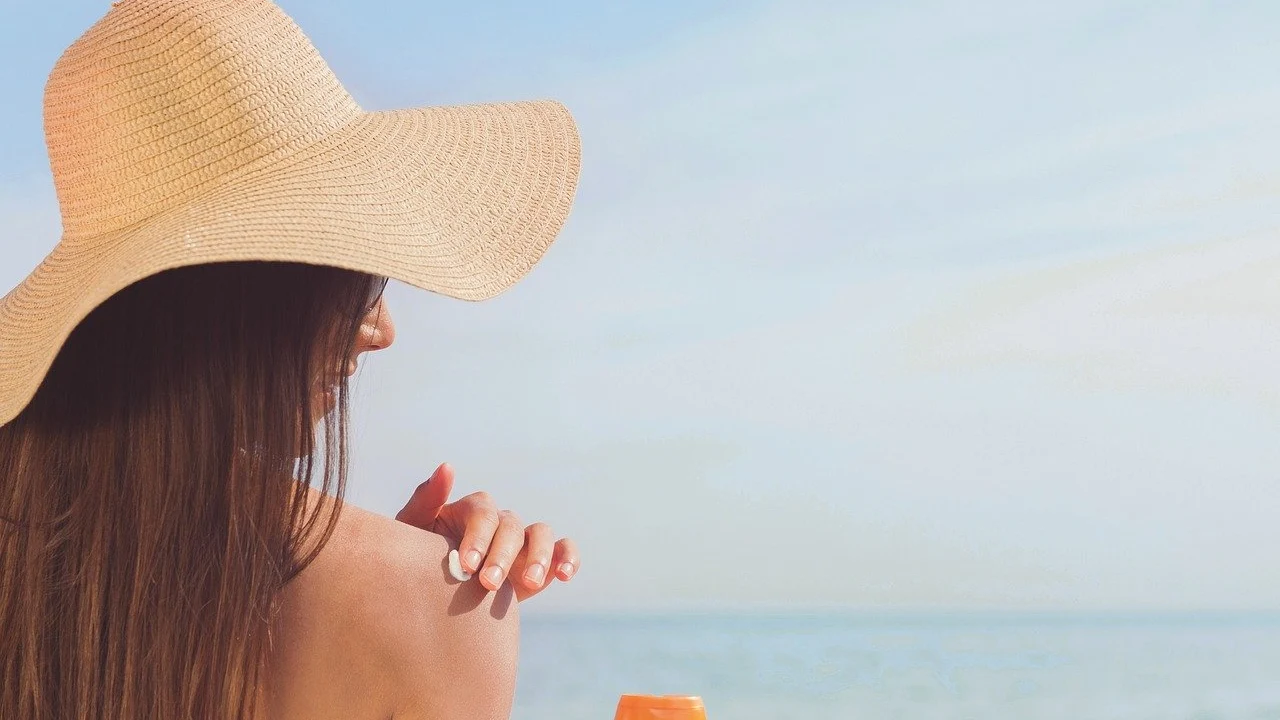 Mujer echándose crema solar en la playa Mujer echándose crema solar en la playa