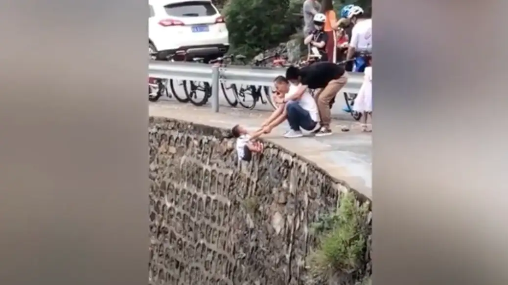 El padre colocando al niño en el acantilado El padre colocando al niño en el acantilado